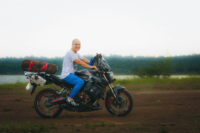 Bald person riding a motorcycle with luggage
